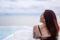 A woman relaxing in infinity swimming pool looking at a beautiful sea view Royalty Free Stock Photo