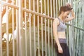 Young asian woman relaxing after jogging exercise stand against steel in park to freshen her body and enjoy warm light in morning.