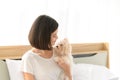 Young Asian woman relaxing and playing with white maltese dog in bedroom at home, Cheerful and nice couple with people and pet. Royalty Free Stock Photo