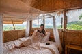 Young asian woman resting and reading a book on the bed in thatched hut among the mountain on vacation Royalty Free Stock Photo