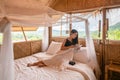 Young asian woman resting and reading a book on the bed in thatched hut among the mountain on vacation Royalty Free Stock Photo