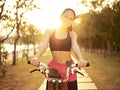 Young asian woman riding bike outdoors at sunset