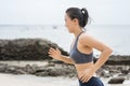 Young Asian woman running on the beach. Girl jogging workout in seaside. Royalty Free Stock Photo