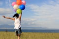 Young asian woman running on sunset grassland with colored balloons Royalty Free Stock Photo