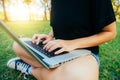 Young asian woman`s legs on the green grass with open laptop. Girl`s hands on keyboard. Distance learning concept. Royalty Free Stock Photo