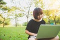 Young asian woman`s legs on the green grass with open laptop. Girl`s hands on keyboard. Distance learning concept. Royalty Free Stock Photo