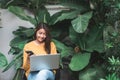 Young Asian woman shopping online with her laptop in a coffee shop garden.