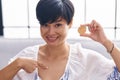 Young asian woman with short hair holding tron cryptocurrency coin pointing finger to one self smiling happy and proud