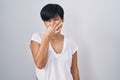 Young asian woman with short hair standing over isolated background smelling something stinky and disgusting, intolerable smell, Royalty Free Stock Photo