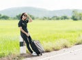 Woman with luggage hitchhiking along a road Royalty Free Stock Photo