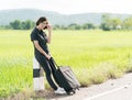 Woman with luggage hitchhiking along a road Royalty Free Stock Photo