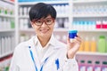 Young asian woman with short hair working at pharmacy drugstore holding cream jar looking positive and happy standing and smiling Royalty Free Stock Photo