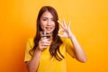 Young Asian woman show OK with a glass of drinking water in yell Royalty Free Stock Photo