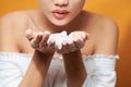 Young Asian woman showing foaming cleanser on her hand while wearing a bath towel over orange background