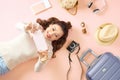 Young Asian woman showing her smartphone while lying on pink floor with travel luggage surround. Top view Royalty Free Stock Photo