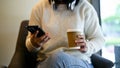 A young Asian woman sipping coffee and using her smartphone in a coffee shop Royalty Free Stock Photo