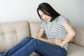 Young asian woman sit on sofa in the living room , women having painful stomachache