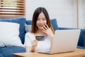 Young asian woman sit on sofa using laptop computer shopping online with credit card buy to internet. Royalty Free Stock Photo