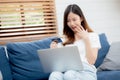 Young asian woman sit on sofa using laptop computer shopping online with credit card buy to internet and surprise. Royalty Free Stock Photo