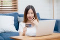 Young asian woman sit on sofa using laptop computer shopping online with credit card buy to internet and surprise. Royalty Free Stock Photo