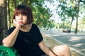 Young Asian woman sitting alone on the public bench in the park surrounded with nature and warm sunlight. Royalty Free Stock Photo