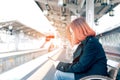 Young asian woman sitting on bench waiting for train and using m Royalty Free Stock Photo