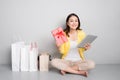 Young asian woman sitting besides row of shopping bags holding r Royalty Free Stock Photo