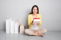 Young asian woman sitting besides row of shopping bags holding r Royalty Free Stock Photo