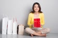 Young asian woman sitting besides row of shopping bags holding r Royalty Free Stock Photo