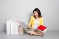 Young asian woman sitting besides row of shopping bags holding r Royalty Free Stock Photo