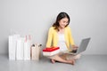 Young asian woman sitting besides row of shopping bags holding r Royalty Free Stock Photo