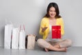 Young asian woman sitting besides row of shopping bags holding r Royalty Free Stock Photo