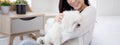 Young asian woman sitting carrying with fluffy dog shih tzu with love in bedroom at home.