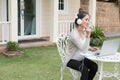 Young asian woman sitting on chair listening to music and using Royalty Free Stock Photo