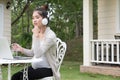 Young asian woman sitting on chair listening to music and using Royalty Free Stock Photo