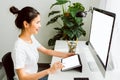 Young Asian woman sitting on chair and look at the computer and touching digital tablet with blank screen in home. Royalty Free Stock Photo