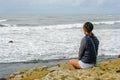 Young Asian woman sitting on a cliff and looking far away at the sea Royalty Free Stock Photo
