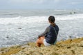 Young Asian woman sitting on a cliff and looking far away at the sea Royalty Free Stock Photo