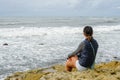 Young Asian woman sitting on a cliff and looking far away at the sea Royalty Free Stock Photo