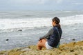 Young Asian woman sitting on a cliff and looking far away at the sea Royalty Free Stock Photo