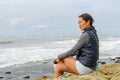 Young Asian woman sitting on a cliff and looking far away at the sea Royalty Free Stock Photo