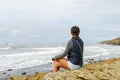 Young Asian woman sitting on a cliff and looking far away at the sea Royalty Free Stock Photo