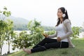 Young asian woman sitting in fresh spring grass listening to mus Royalty Free Stock Photo