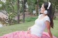 Young asian woman sitting in fresh spring grass listening to mus Royalty Free Stock Photo