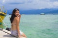 Young Asian woman sitting happy on sea dock at Thailand beach looking at the horizon beautiful marine landscape with mountains enj Royalty Free Stock Photo