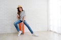 Young asian woman sitting on luggage holding smartphone in white room background, Happy teenage girl tourist in casual sit on Royalty Free Stock Photo