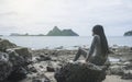 Young asian woman sitting on a rock near the sea,looked to the sea,chill out of summer,rest time,light effect added Royalty Free Stock Photo