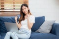 Young asian woman sitting thinking idea using credit card with laptop computer on couch, girl shopping online. Royalty Free Stock Photo