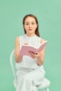 A young asian woman sitting and writing her notes isolated over blue background Royalty Free Stock Photo