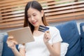 Young asian woman smiling holding credit card shopping online with tablet computer buying and payment. Royalty Free Stock Photo